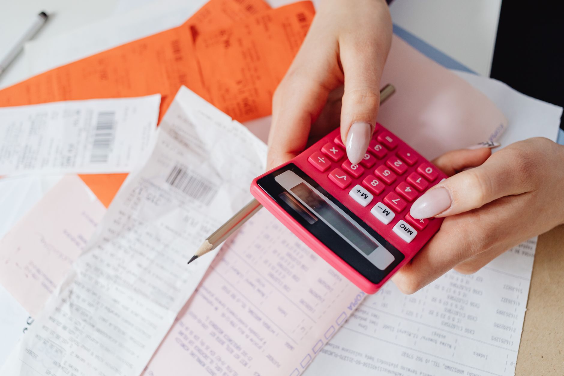 Mains détaillant une facture à la calculatrice, équipe MSF en arrière-plan